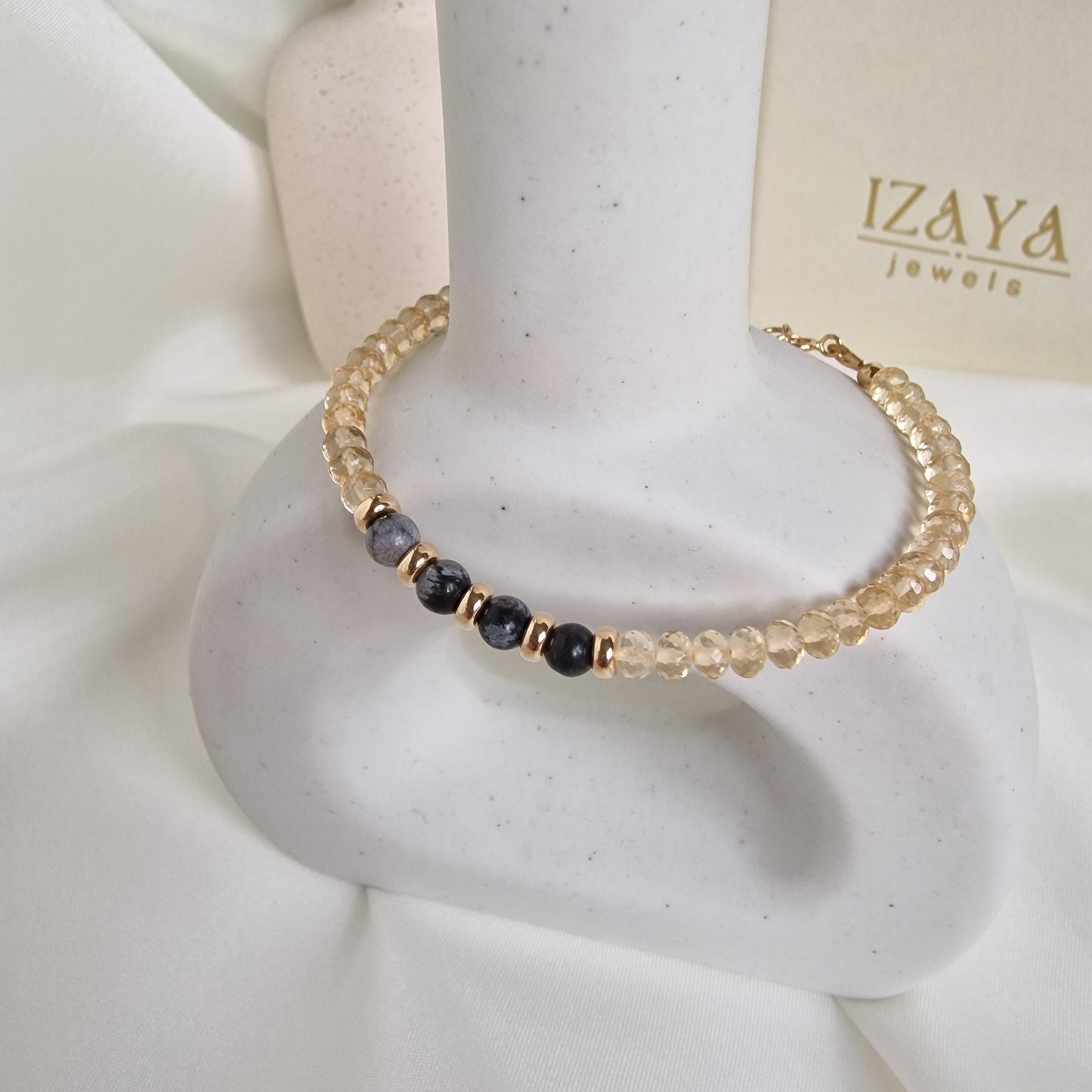 Beaded bracelet on a mannequin hand with 'IZAYA' branding in the background