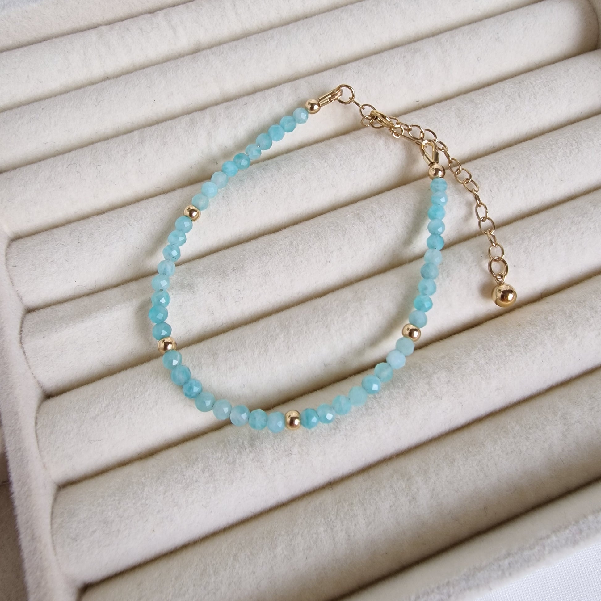 Turquoise beaded bracelet with gold accents on a white textured surface
