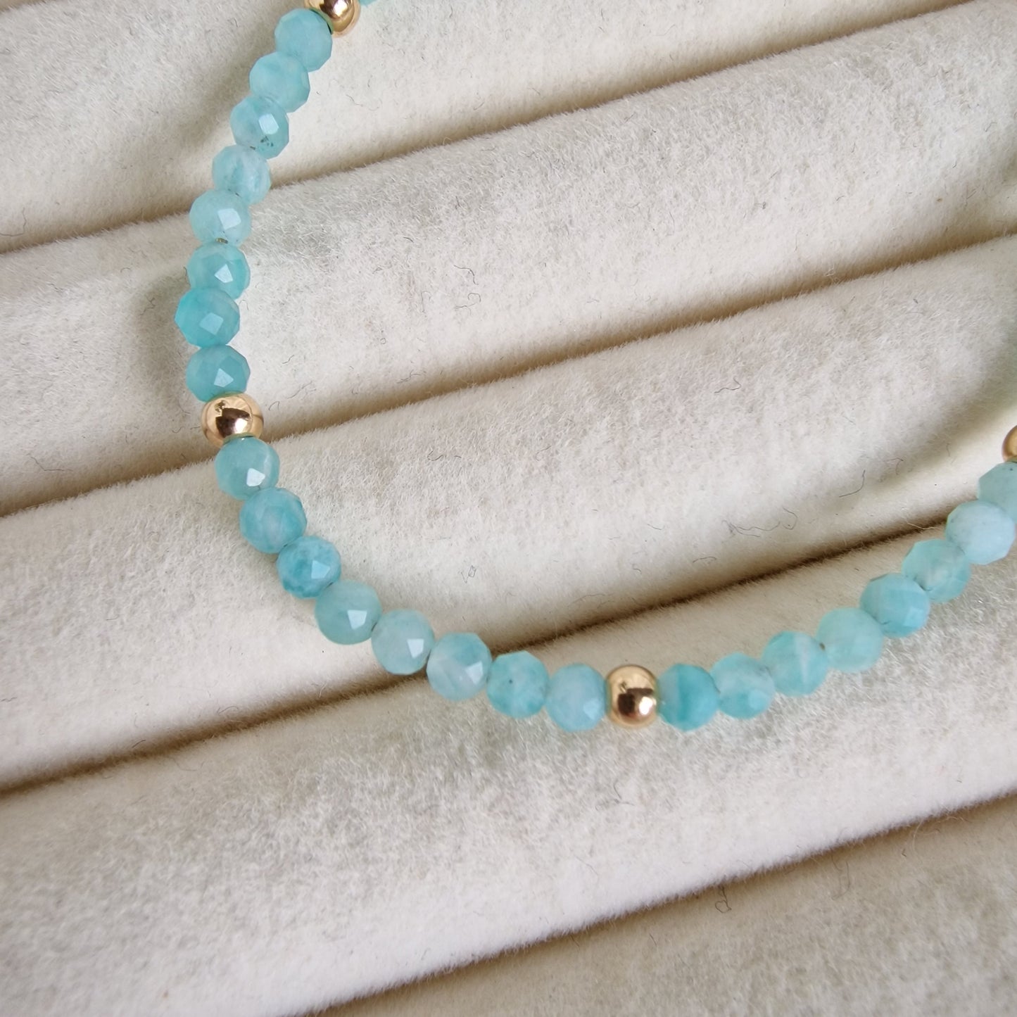 Turquoise beaded bracelet with gold accents on a beige fabric background