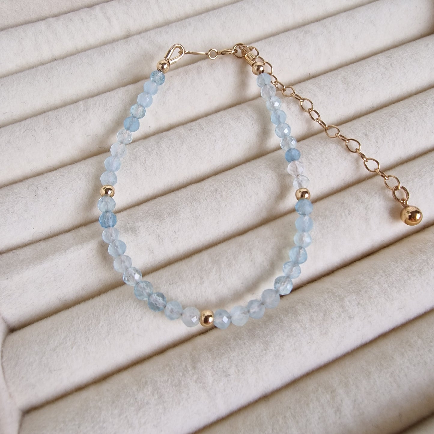 Bracelet with blue beads and gold accents on a beige fabric background