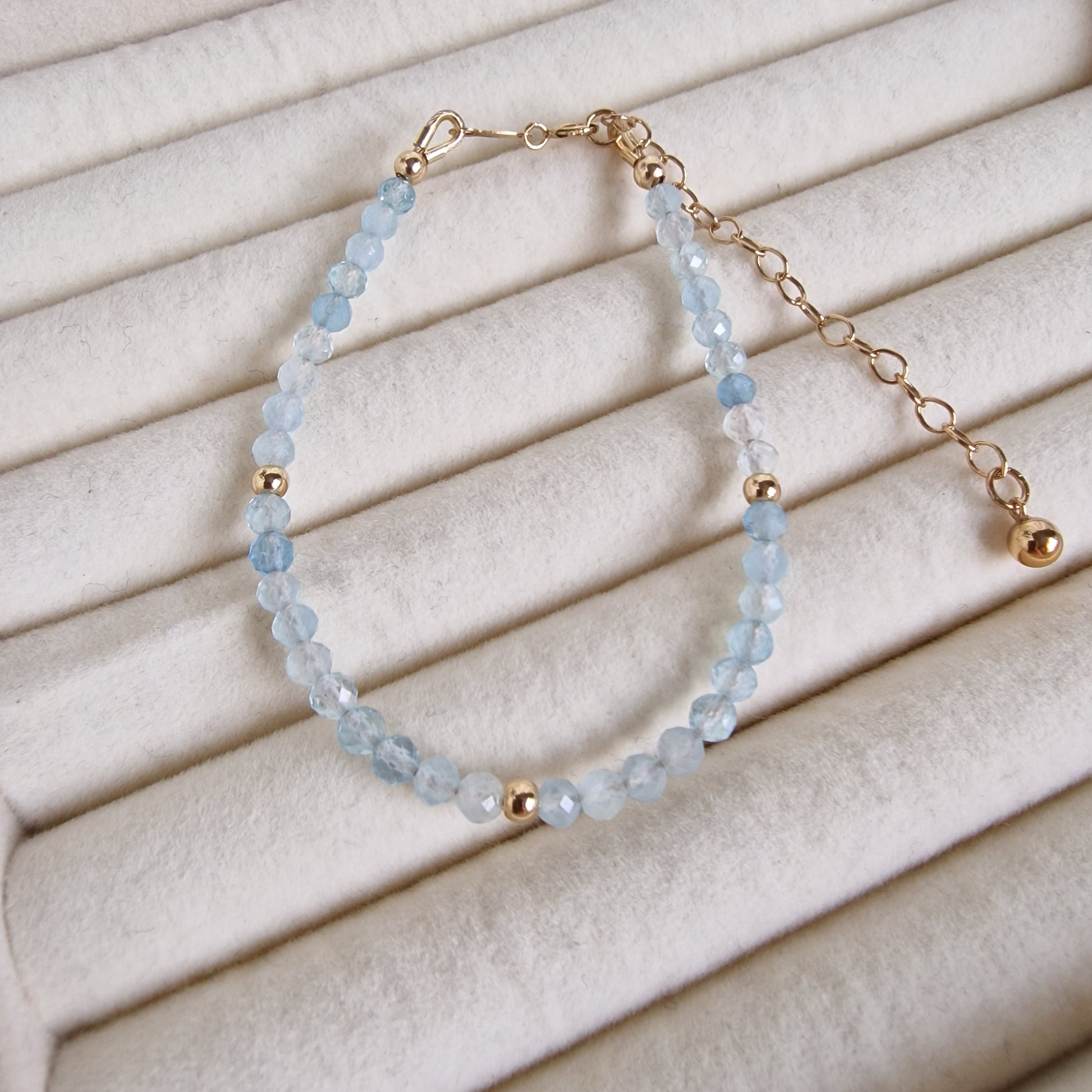 Bracelet with blue beads and gold accents on a beige fabric background